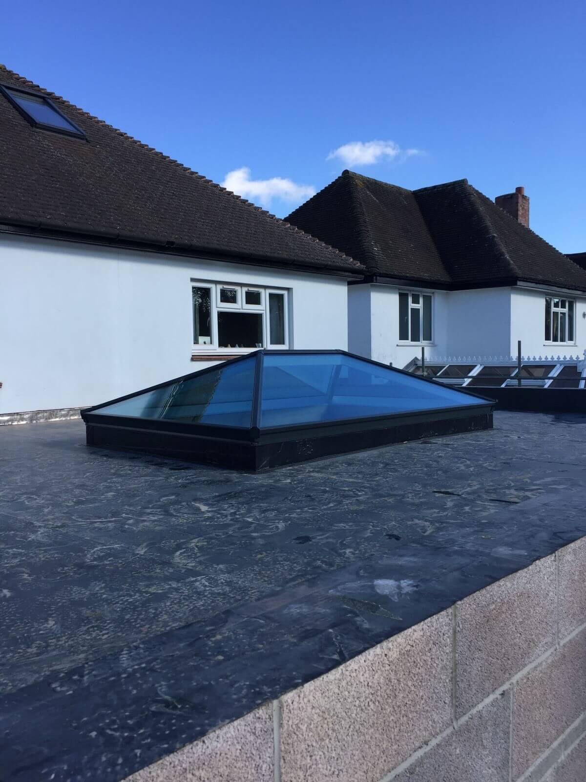 A glass skylight installed on a house roof, allowing natural light to enter the interior space.